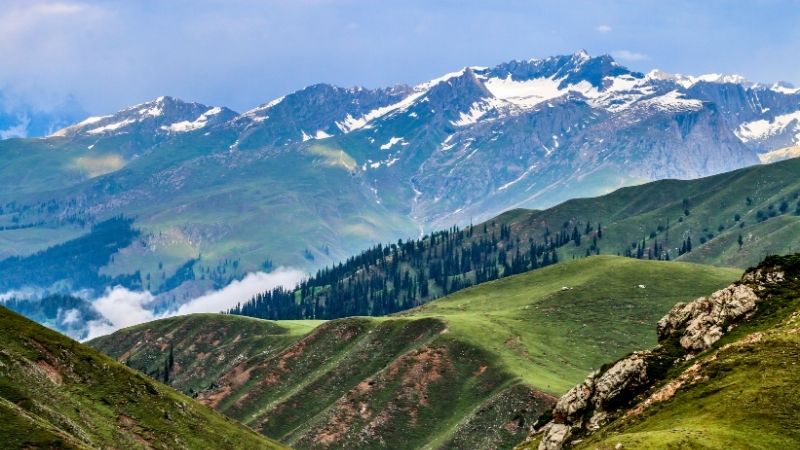 Snow capped mountains and green hills in Kumrat, Swat Valley Pakistan.